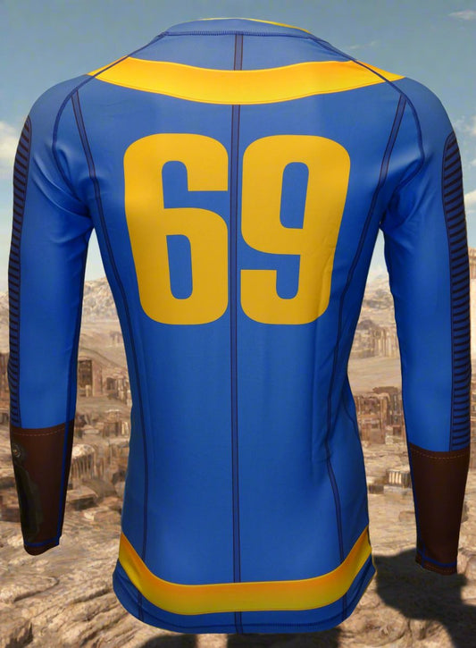 The Retro Grappler Fallout Vault Dweller Rash Guard is a limited edition blue long-sleeve with yellow stripes and a bold number 69 on the back, inspired by Fallout’s iconic look and set in a rocky, desert-like landscape.