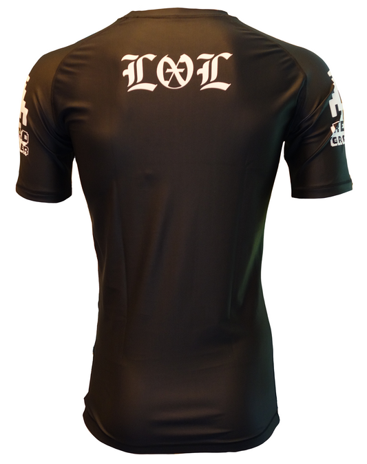 The LOL Rash Guard by Retro Grappler is a black short-sleeve jiu-jitsu top, seen from the back with stylized white LOL on the upper back and Retro Grappler-inspired white graphics on both sleeves.