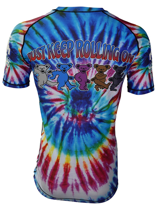 The Retro Grappler Reaping Leg Tye Dye Rash Guard showcases five colorful dancing bears and JUST KEEP ROLLING ON on the back, blending Grateful Dead vibes with BJJ culture in a bold tie-dye design.