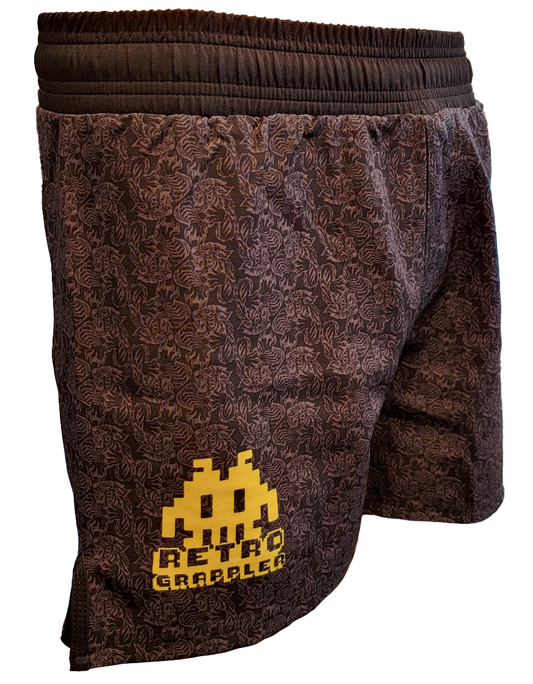 The Tiger Pressure Grappling Shorts by Retro Grappler feature a black patterned design with yellow pixel accents and Retro Grappler on the left leg. These lightweight shorts have no Velcro, providing a comfortable, secure fit during training.
