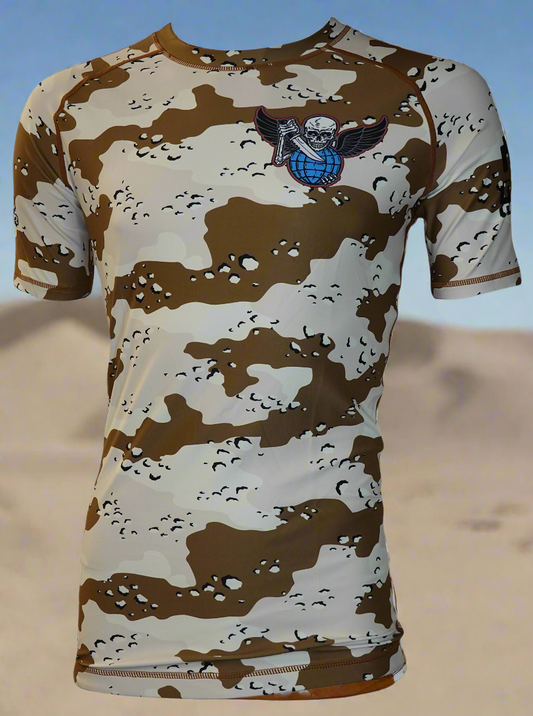 The Retro Grappler Operation Mat Storm Desert Camo Rash Guard features short sleeves, tan and brown desert camo, and a winged skull over a blue globe logo on the chest—ideal for jiu jitsu fans.