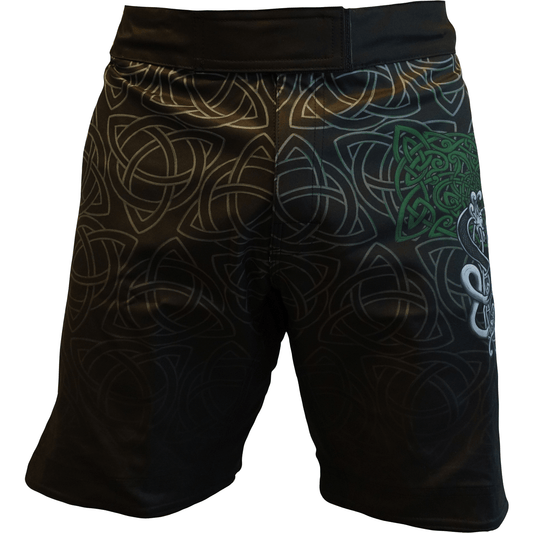 The Retro Grappler Celtic Luck Fight Short is black with an intricate gray Celtic knot pattern, a green trinity knot, and a white design on the right leg.