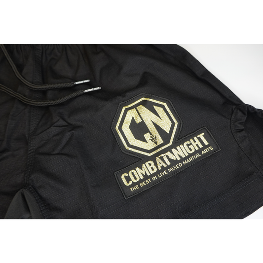 The Retro Grappler Combat Night Gi Shorts are black, lightweight rip-stop shorts with a drawstring and a gold Combat Night logo patch reading The Best in Live Mixed Martial Arts.