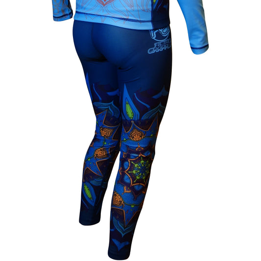 A person shown from the back wears Retro Grappler’s Zen Line: Mandala Women’s Spats—a blue, long-sleeve rash guard and matching leggings with colorful geometric and mandala patterns—against a white background.