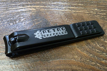 Black nail clipper with 'Retro Grappler' branding on a wooden surface