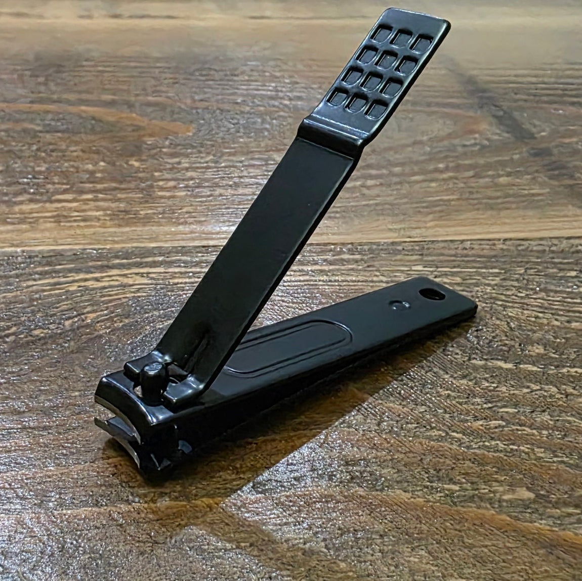 Black nail clipper on a wooden surface