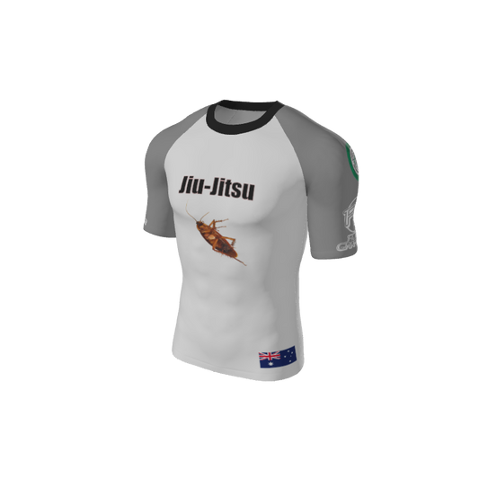 The Custom Retro Grappler Custom Single Color Short Sleeve Rash Guard features a white and gray design with Jiu-Jitsu text, a cockroach image, Australian flag patch, and green/white sleeve logos—perfect for stand-out style and performance.